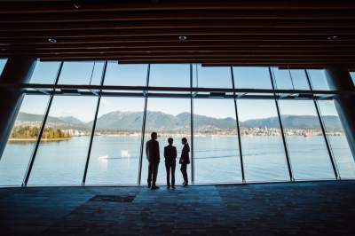 Trois personnes regardent les montagnes de Vancouver à travers une fenêtre.