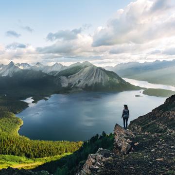 Hiker stands on rocky outcropping overlooking forests, mountains, and a fjord