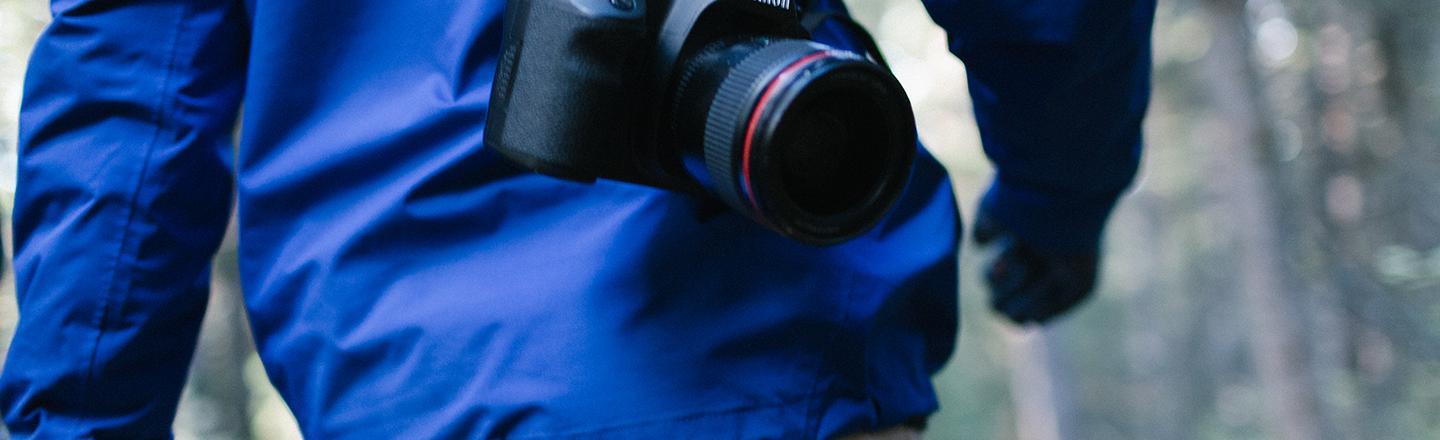 A person walking with a camera on a strap around their back