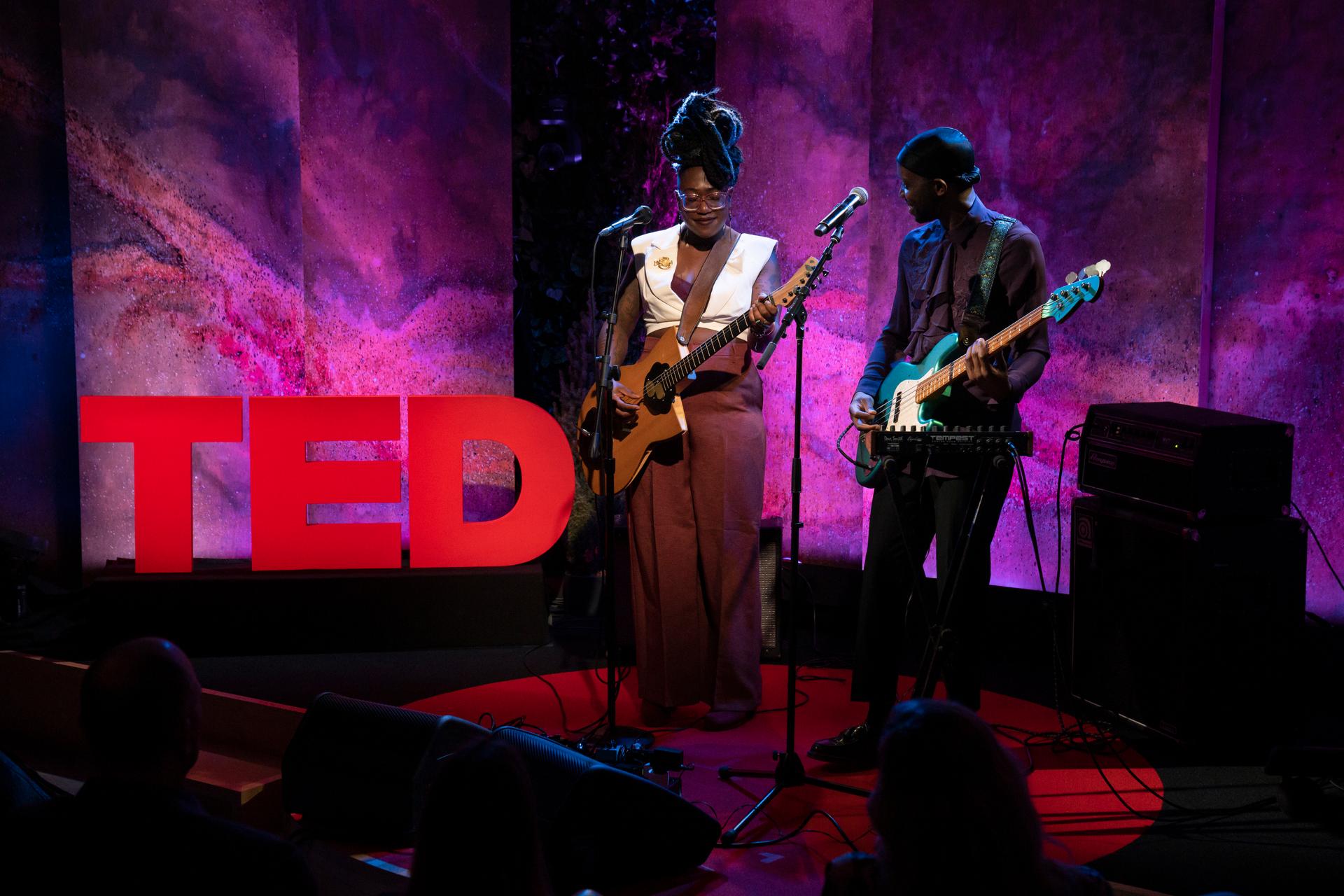 A singer and guitar player performing on the TED stage.