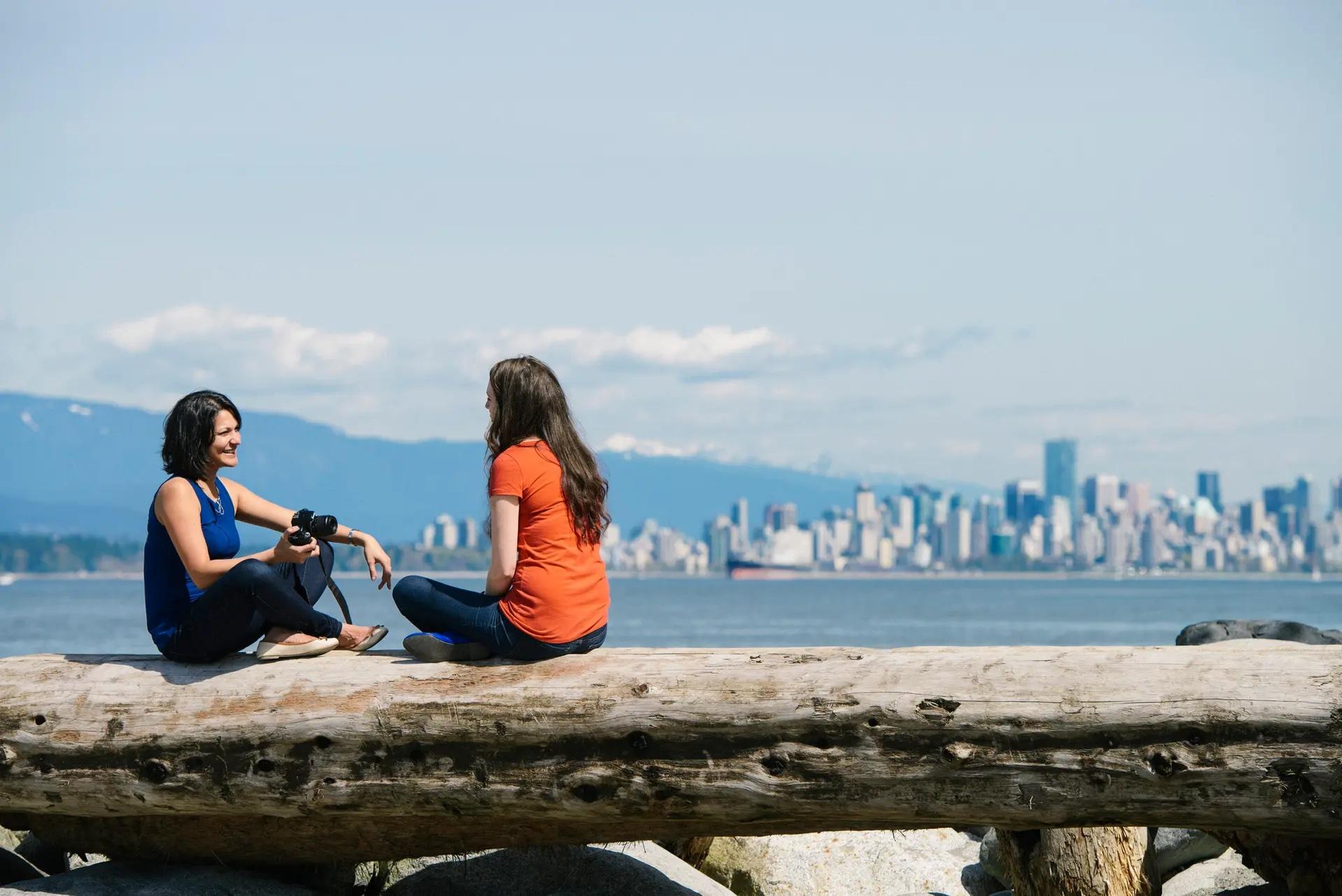 Two people sitting on the seawall at Jericho beach
