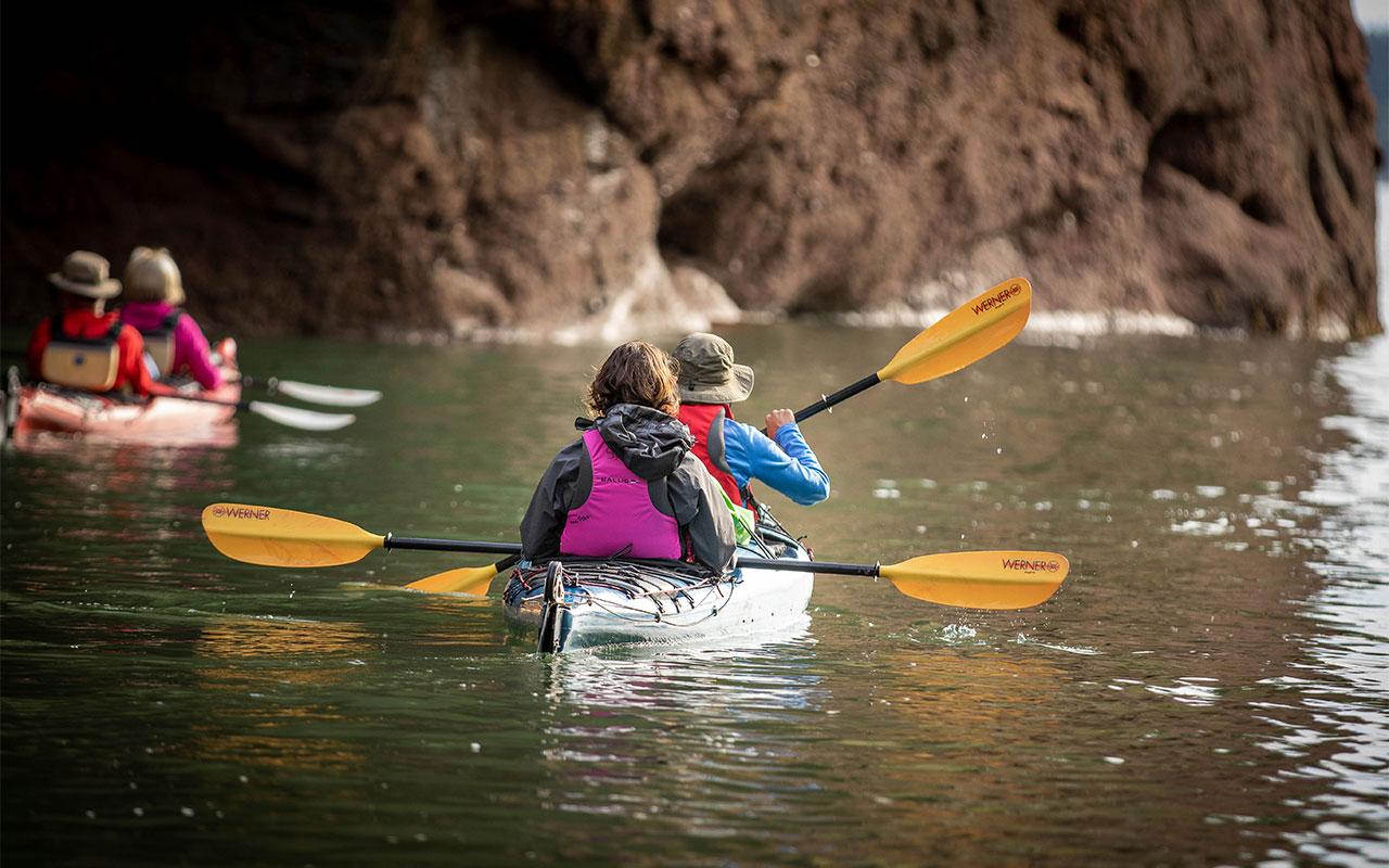 Kayakers paddling near sea caves in St. Martins on the Bay of Fundy.