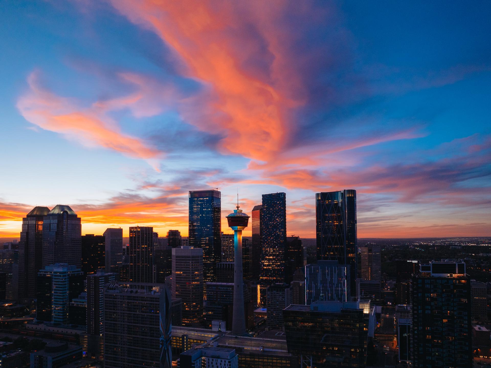 Calgary skyline at sunset with colorful pink and blue clouds above downtown buildings and the Calgary Tower