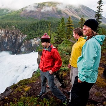 3 personnes regardent une cascade avec des vestes colorées